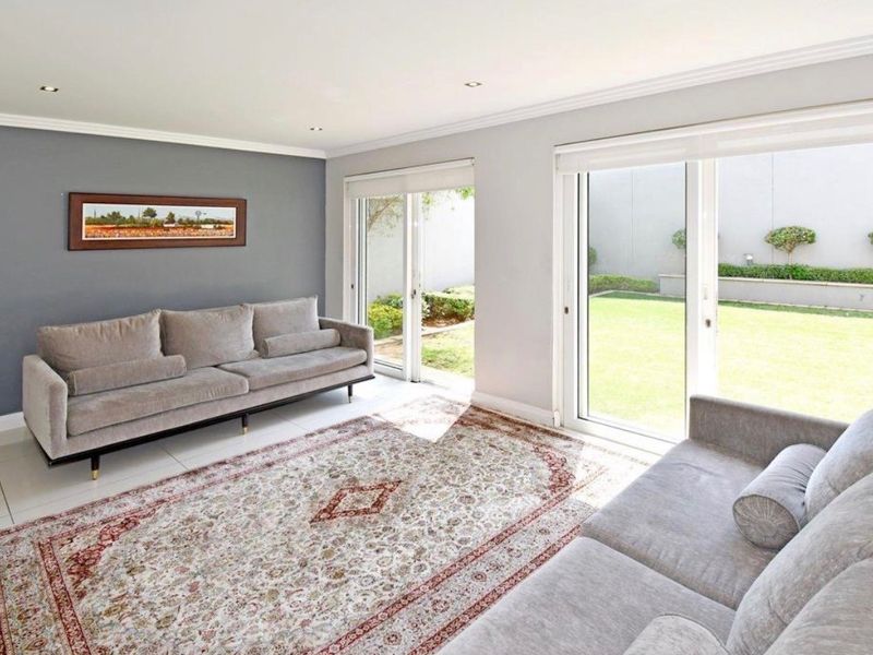Bright living room featuring tiled flooring, recessed downlights, and large sliding glass doors providing direct access to the rear garden.