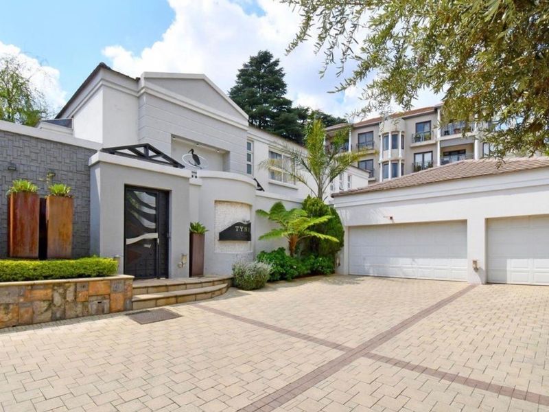 Front elevation of a townhouse featuring a paved driveway, double garage, and a modern entrance with stone cladding accents.