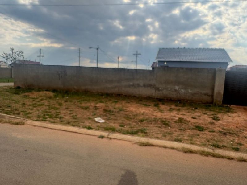 Street view showing the property boundary wall, metal gate, and adjacent road frontage.