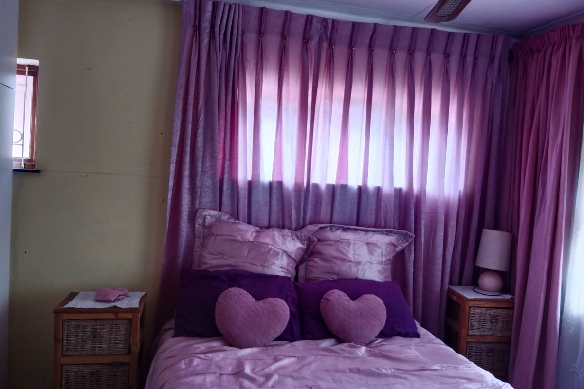 A bedroom featuring a ceiling fan and window with floor-to-ceiling curtains.