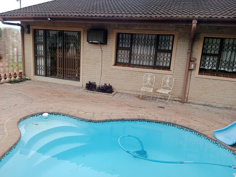 Rear exterior view featuring a swimming pool with brick paving, sliding door access, and a classic brick facade with security gates.