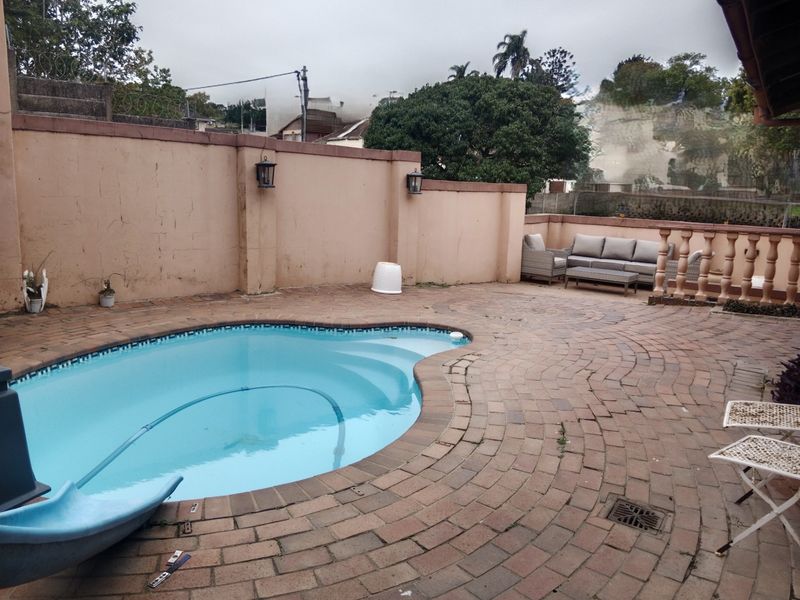 Outdoor pool area featuring a paved patio, perimeter wall with lighting, and a balustrade, offering a functional space for outdoor relaxation.