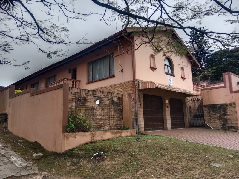 Front elevation of a double-story house featuring a double garage, paved driveway, and brick boundary walling.
