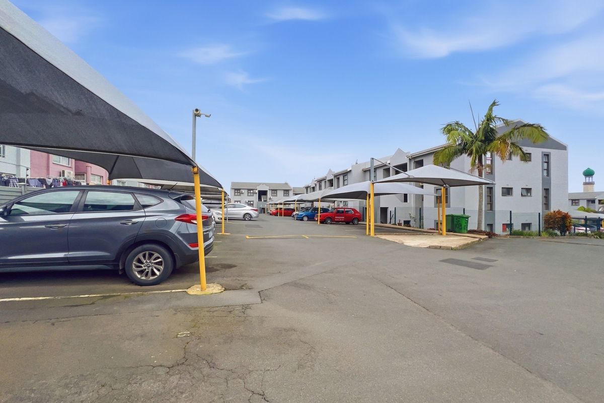 Exterior view of the apartment complex parking area featuring multiple shade cloth carports and paved driveway surfaces.