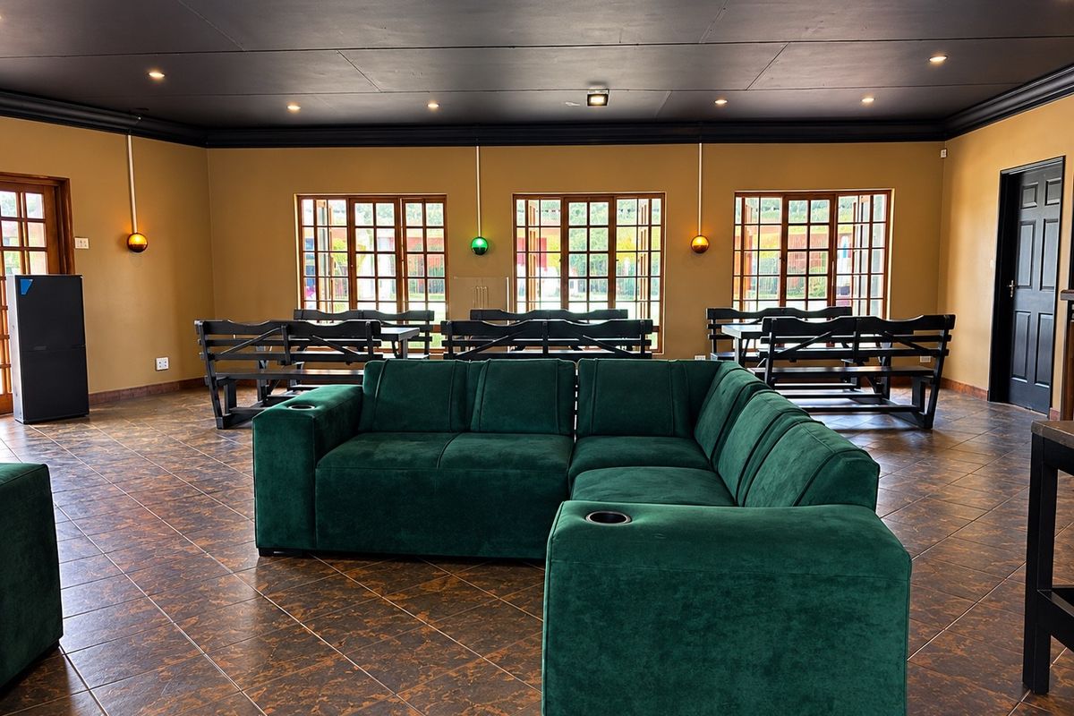 Spacious commercial living area featuring dark tiled flooring, timber-framed windows, and modern recessed ceiling lighting with a bold black ceiling finish.