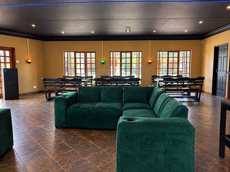 Spacious commercial living area featuring dark tiled flooring, timber-framed windows, and modern recessed ceiling lighting with a bold black ceiling finish.