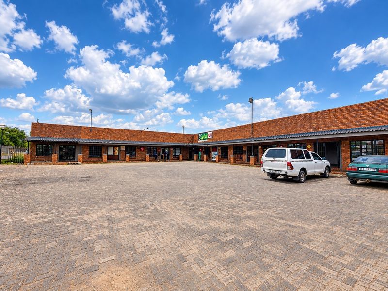 A commercial property featuring a brick facade with a covered walkway and a large paved parking area.