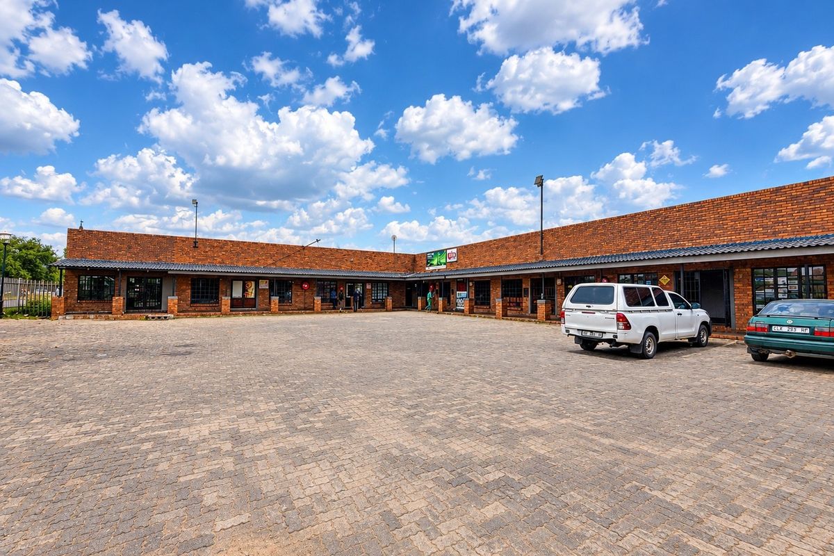 A commercial property featuring a brick facade with a covered walkway and a large paved parking area.