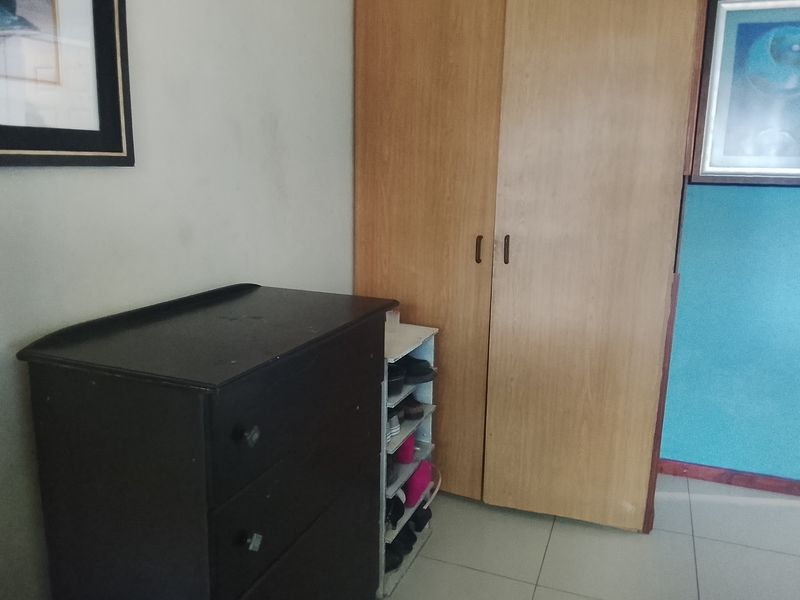 A bedroom interior featuring a built-in wooden wardrobe and tiled flooring.
