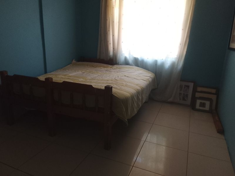 A bedroom featuring tiled flooring and a window with natural light, providing a functional space for rest.