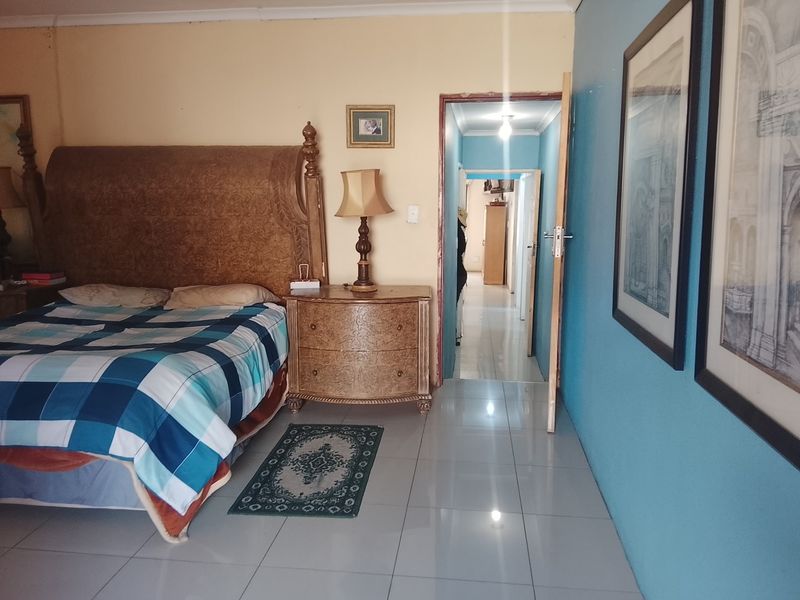 A bedroom featuring tiled flooring and access to an adjoining hallway, with painted walls and standard architectural finishes.