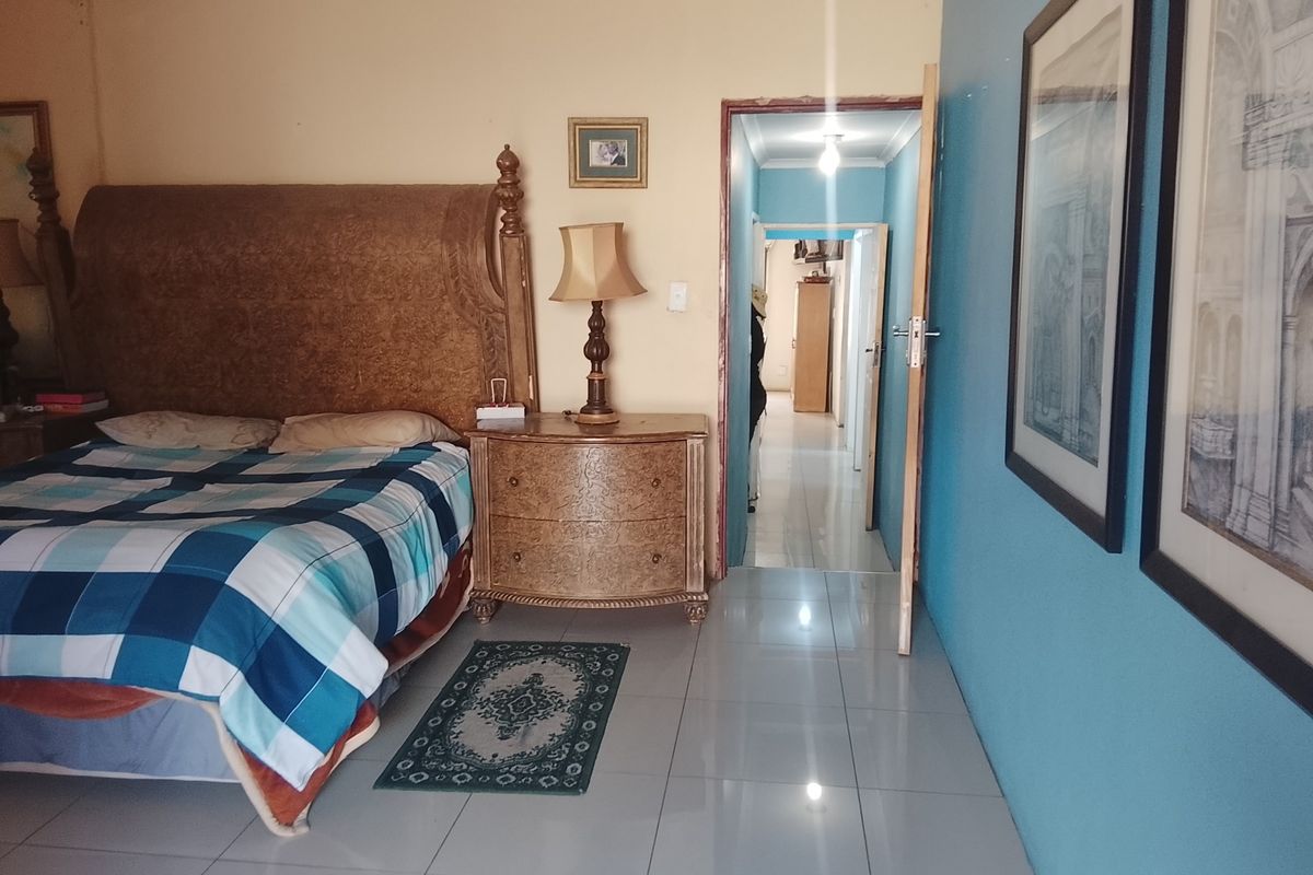 A bedroom featuring tiled flooring and access to an adjoining hallway, with painted walls and standard architectural finishes.