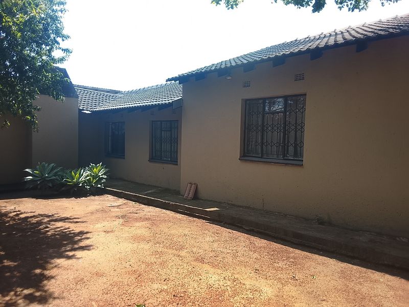 Rear exterior view of the house featuring a tiled roof, security bars on windows, and a concrete apron surrounding the building structure.