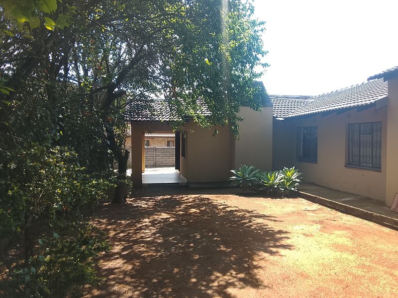 A view of the rear exterior of the house featuring a covered walkway, tiled roof, and security bars on the windows.