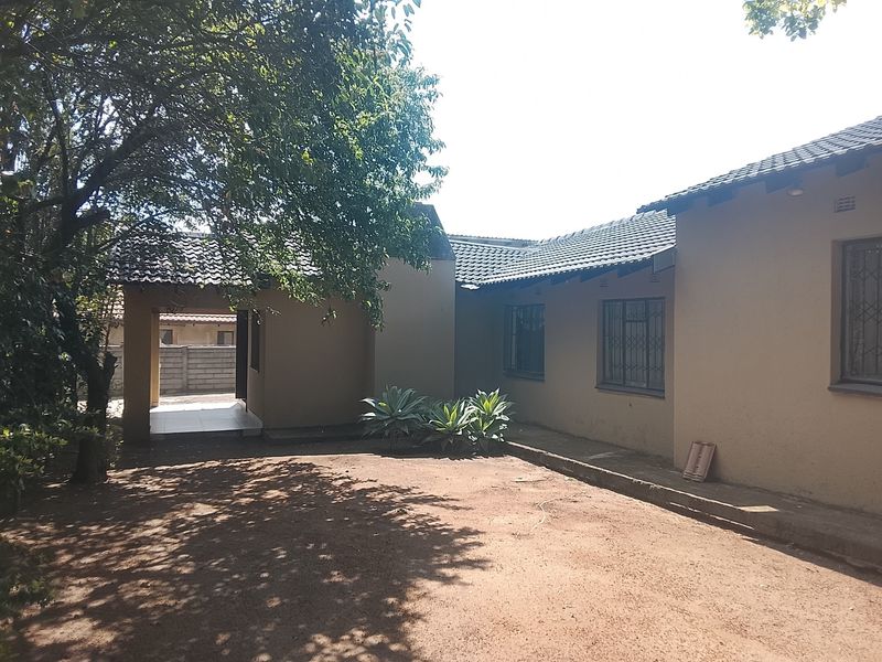 Rear view of the house featuring a tiled roof, security bars on windows, and a covered walkway leading to the entrance.