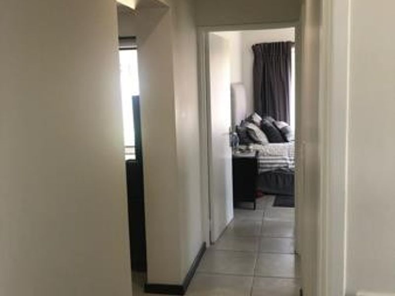 A neutral-toned hallway with tiled flooring, providing access to adjacent rooms within the apartment.