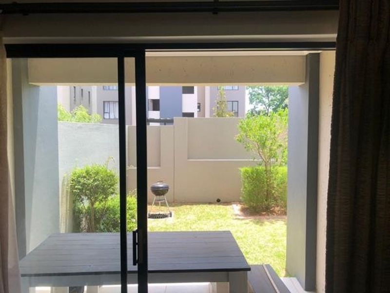 A covered patio area with sliding glass doors leading out to a private, well-maintained garden with boundary walls.