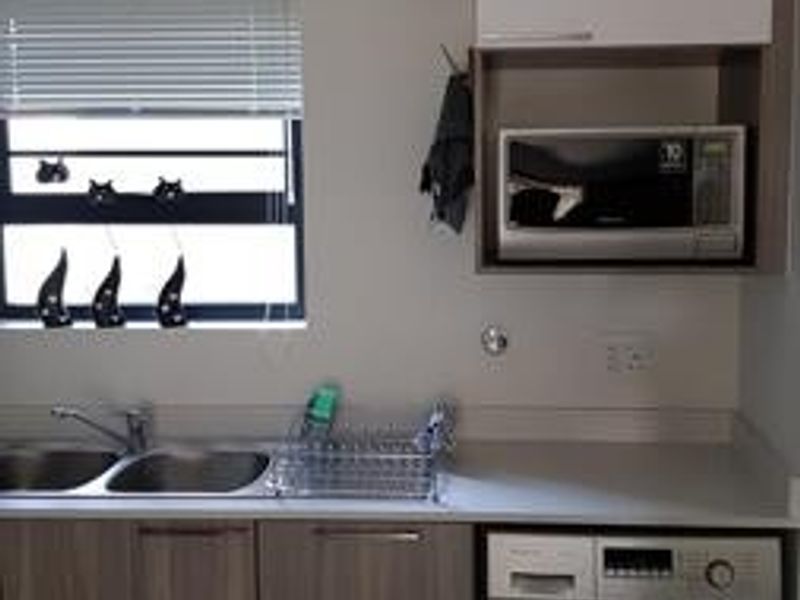 A functional kitchen area featuring built-in cabinetry, a stainless steel sink, a built-in microwave, and an integrated washing machine.