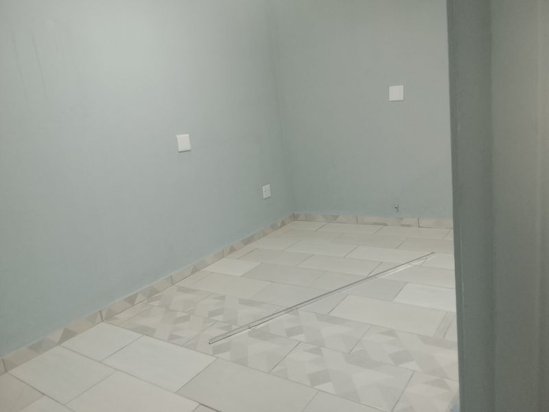 An empty bedroom featuring light-colored tiled flooring and neutral wall paint, providing a blank canvas for interior design.
