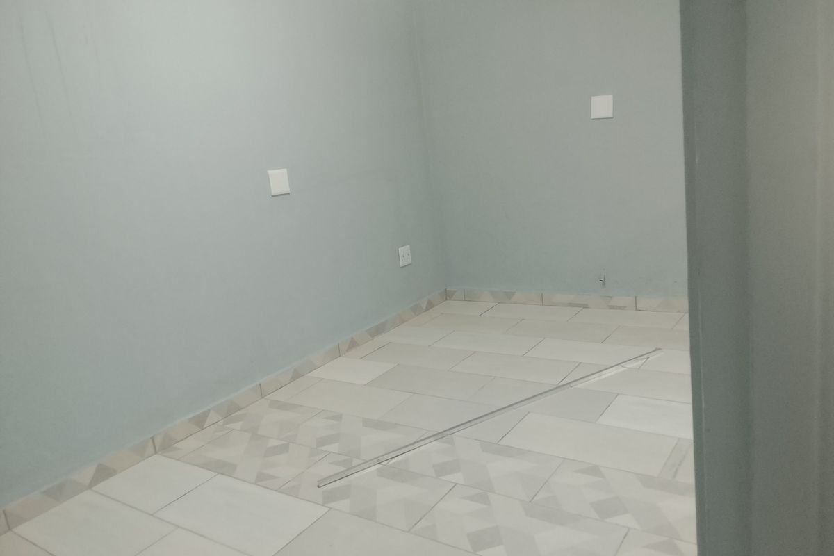 An empty bedroom featuring light-colored tiled flooring and neutral wall paint, providing a blank canvas for interior design.