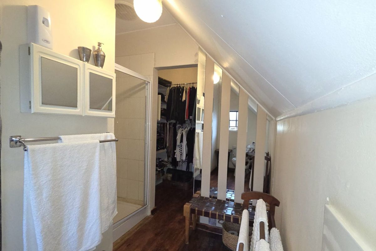 Bathroom featuring a shower enclosure, sloped ceiling, and an integrated walk-in closet area with built-in storage.