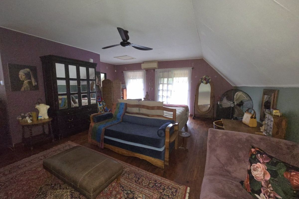 Spacious bedroom featuring hardwood flooring, a sloped ceiling, ceiling fan, and a wall-mounted air conditioning unit.