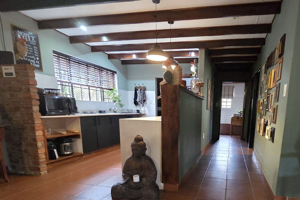 Kitchen area featuring exposed timber ceiling beams, tiled flooring, and a central island, providing a rustic and functional cooking space.