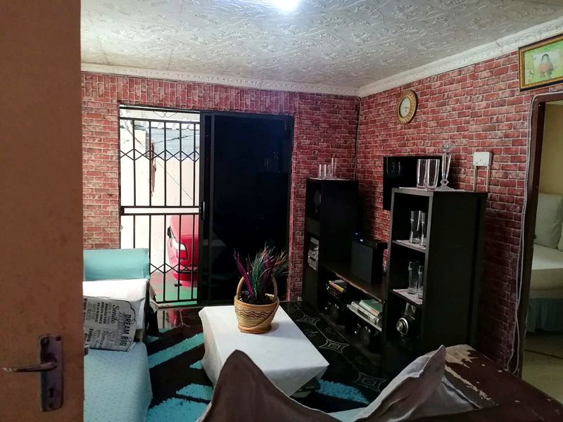 Living room featuring brick-effect wall cladding, a textured ceiling, and a sliding glass door with a security gate leading to the exterior.