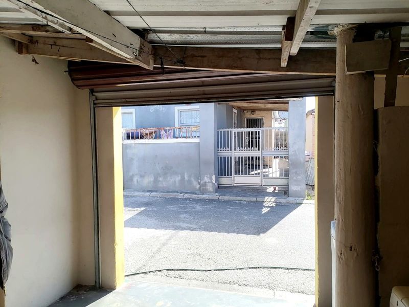 A functional garage space featuring exposed timber roof beams and a roller shutter door, providing secure parking with direct access to the exterior.