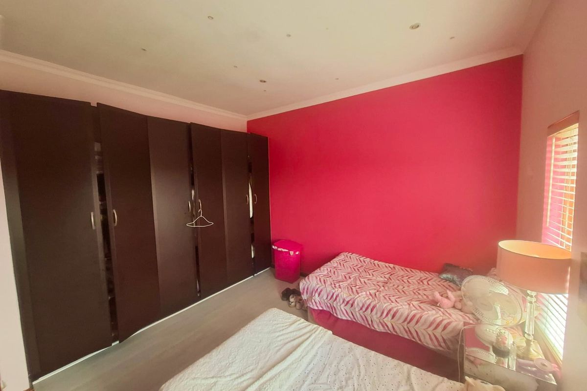 A bedroom featuring built-in dark wood cupboards, recessed ceiling lighting, and venetian blinds, providing ample storage and functional space.