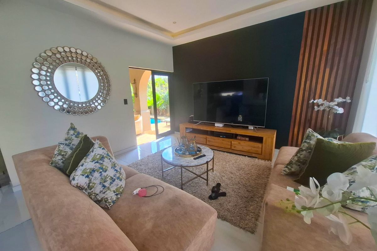 Modern living room featuring a striking timber slat accent wall, recessed ceiling lighting, and large sliding glass doors providing direct access to the outdoor area.