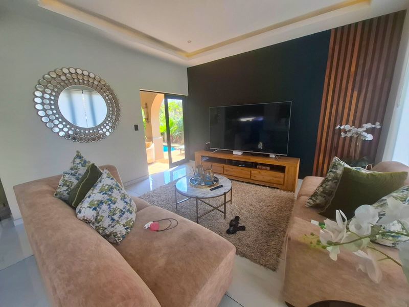 Modern living room featuring a striking timber slat accent wall, recessed ceiling lighting, and large sliding glass doors providing direct access to the outdoor area.