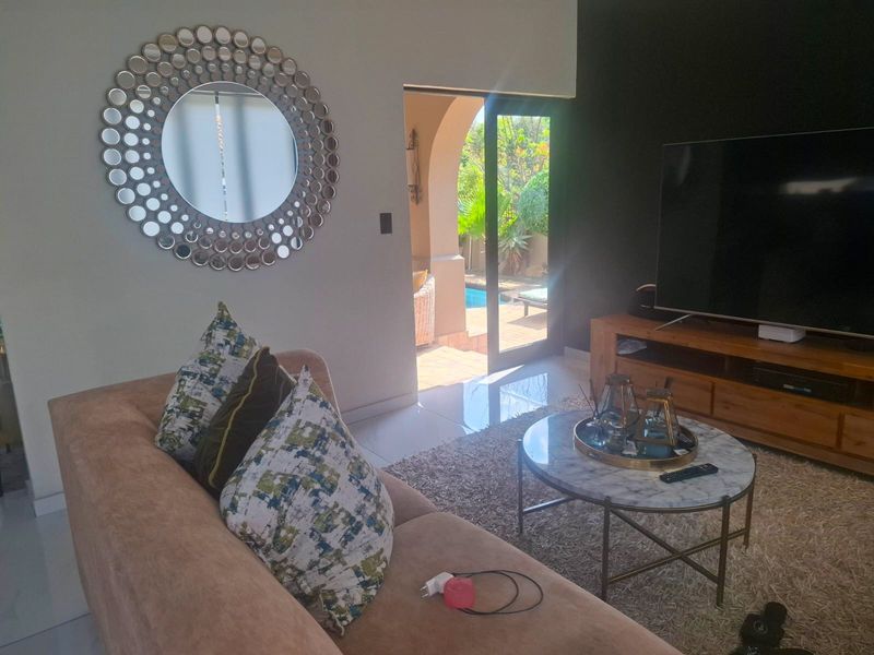 A comfortable living room featuring tiled flooring, a dark accent wall, and direct access to an outdoor patio and pool area.