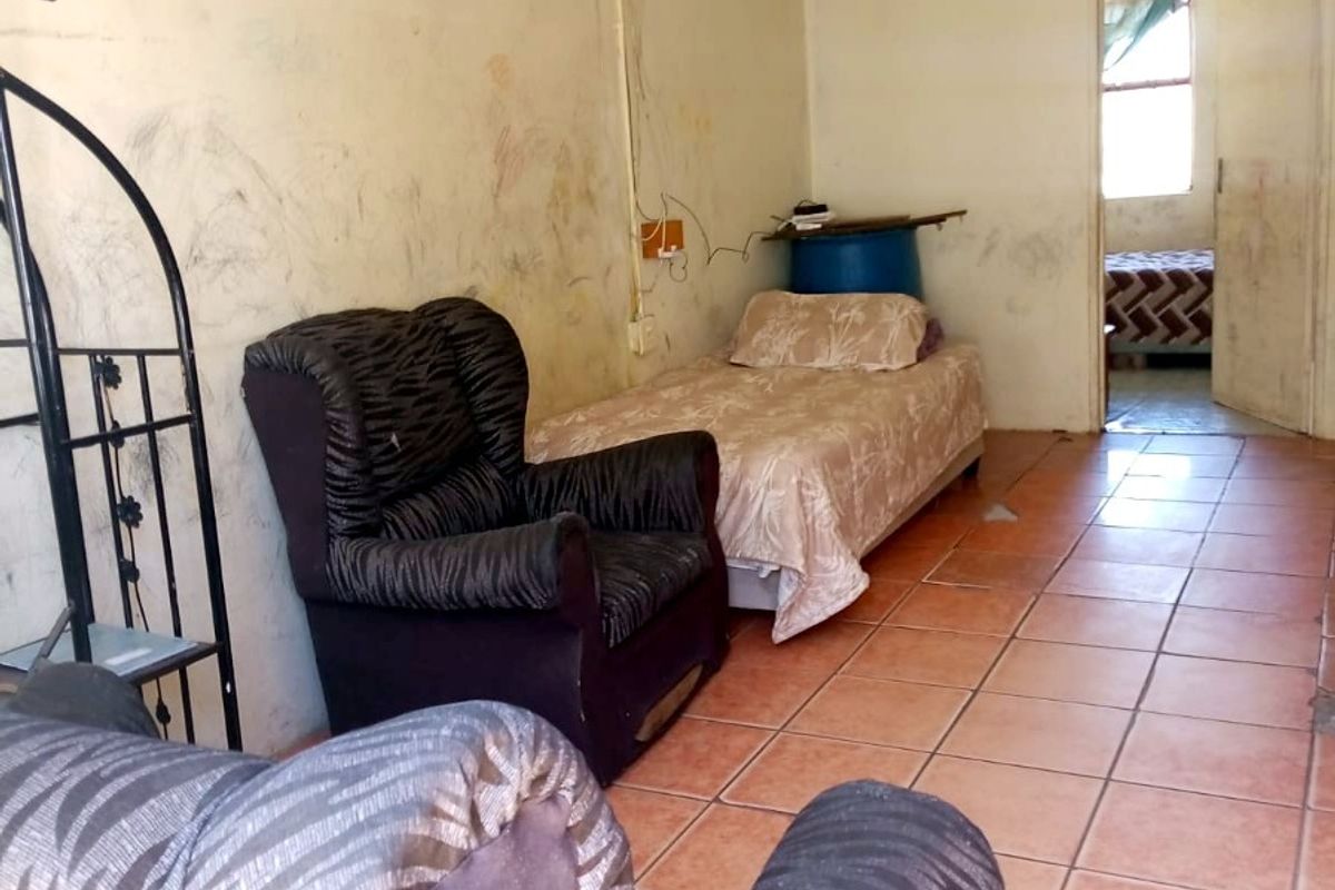 A living area featuring ceramic floor tiles, requiring significant wall and ceiling repairs to improve the overall condition of the space.