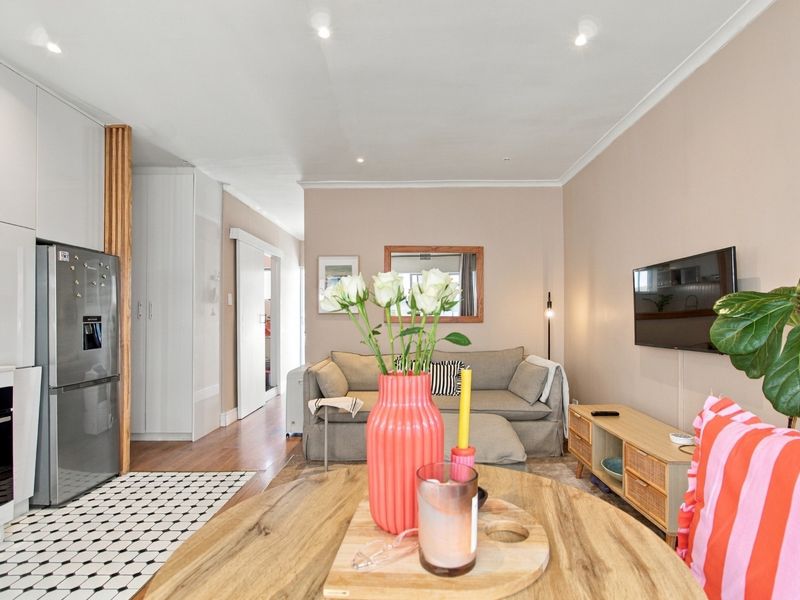 A modern open-plan living and kitchen area featuring sleek cabinetry, recessed lighting, and a seamless transition between the kitchen and lounge space.