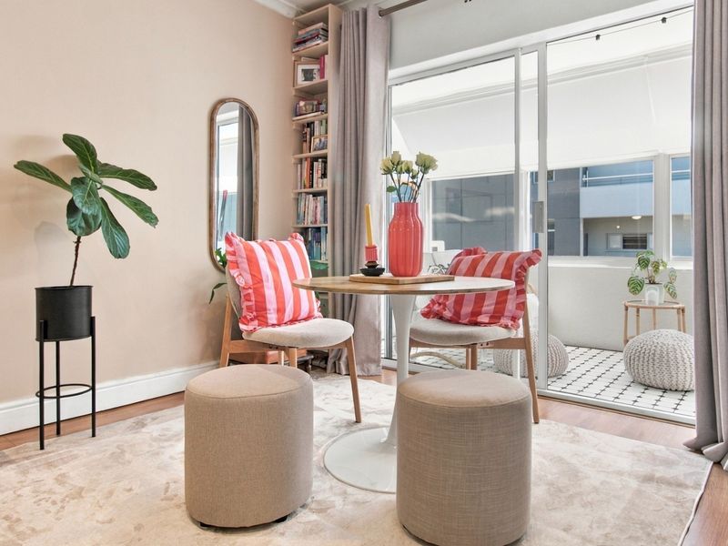 A bright living area featuring laminate flooring, built-in shelving, and a sliding glass door providing access to a private balcony.