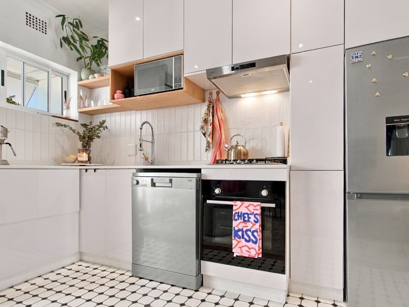 Modern kitchen featuring white high-gloss cabinetry, integrated appliances, a tiled backsplash, and classic patterned floor tiles.