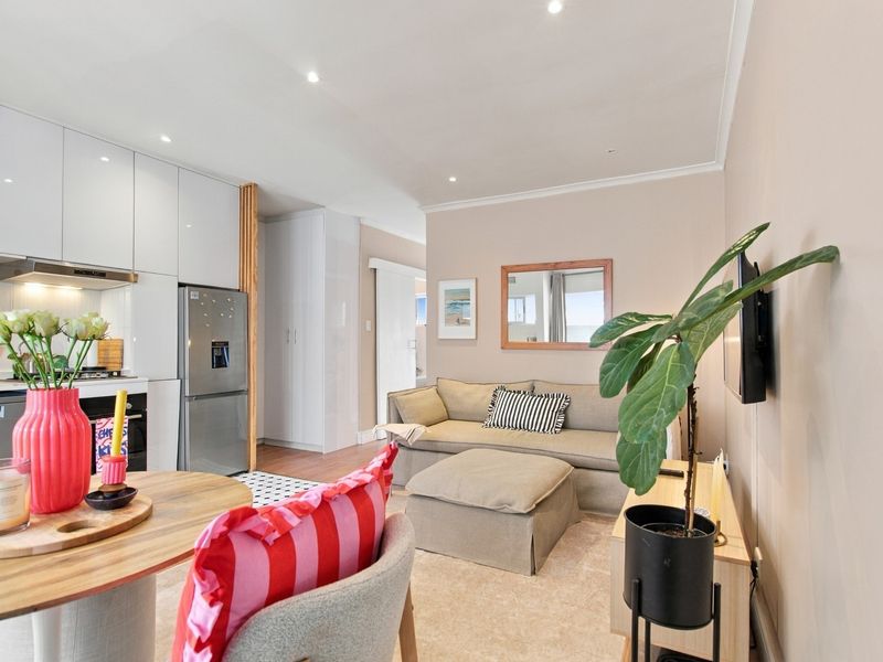 Modern open-plan living area featuring a sleek kitchen with built-in cabinetry and recessed lighting, seamlessly flowing into a comfortable lounge space.