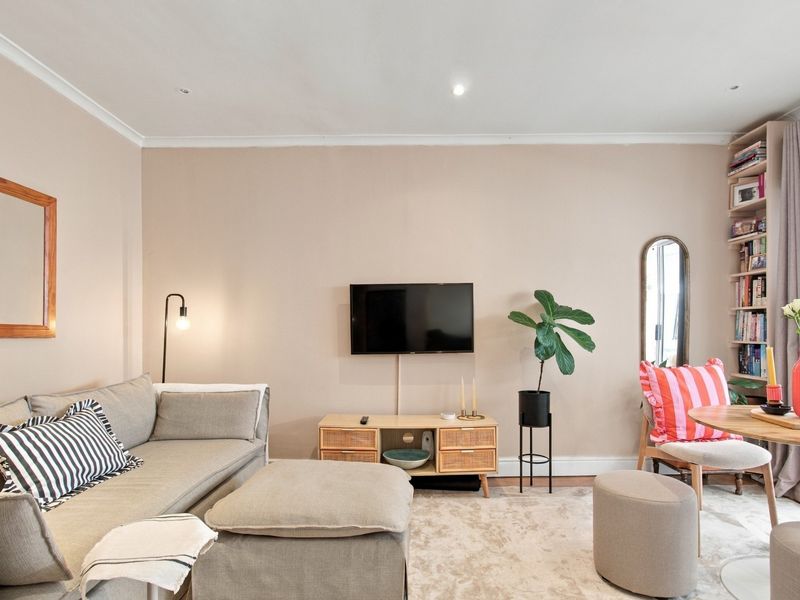 A well-maintained living room featuring recessed downlighting, coving, and a built-in shelving unit, creating a comfortable and functional living space.