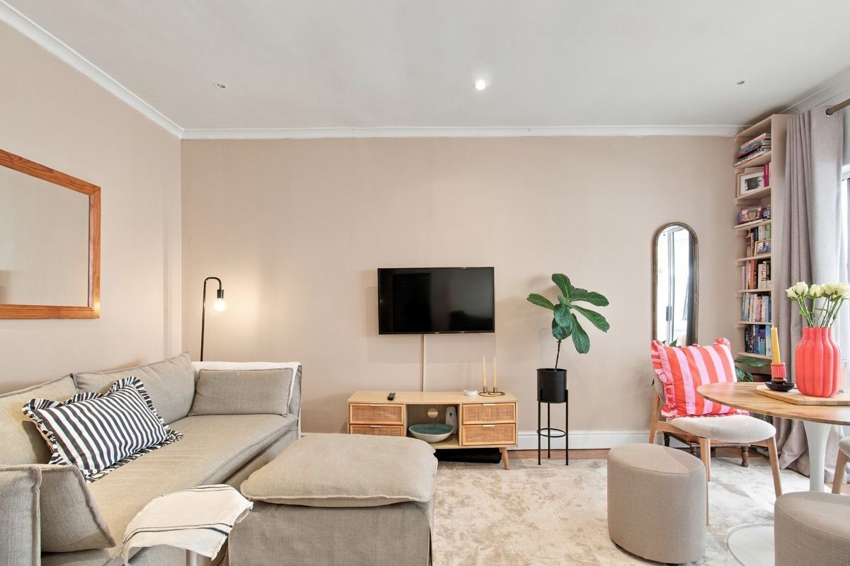A well-maintained living room featuring recessed downlighting, coving, and a built-in shelving unit, creating a comfortable and functional living space.