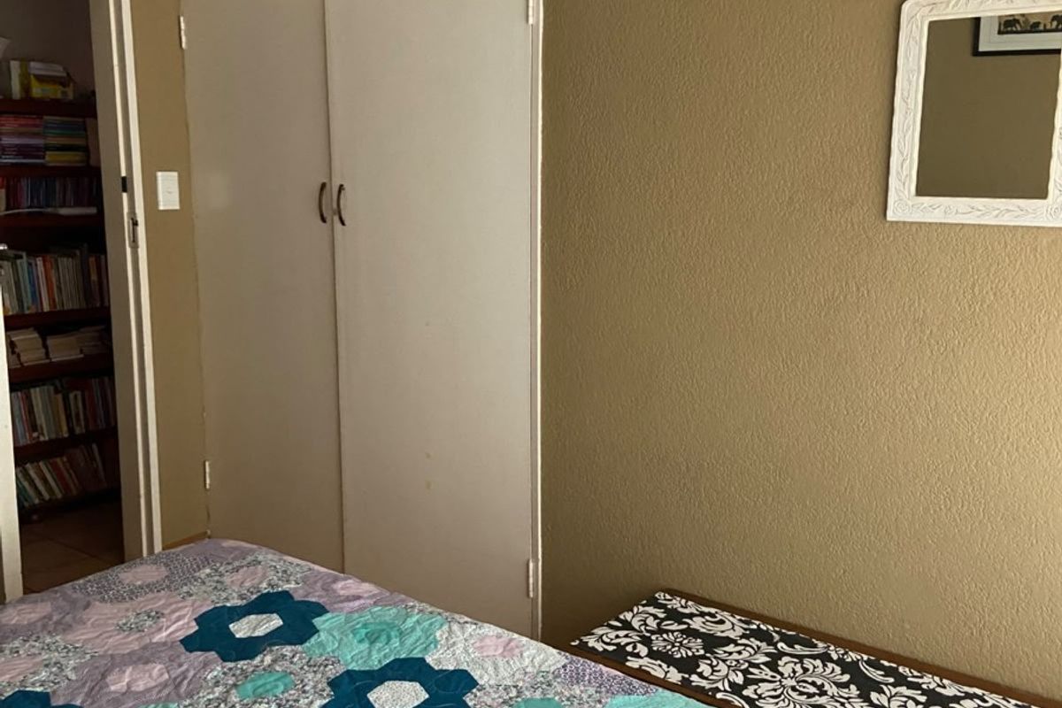 A bedroom featuring built-in cupboards, coving, and wooden flooring, offering a functional space with potential for cosmetic updates.