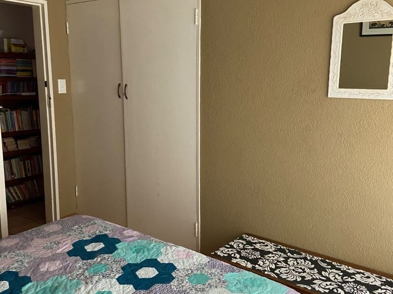 A bedroom featuring built-in cupboards, coving, and wooden flooring, offering a functional space with potential for cosmetic updates.