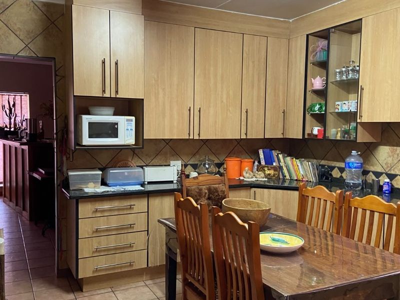 A functional kitchen featuring laminate cabinetry, tiled backsplash, and ceramic flooring, offering a practical layout with integrated microwave space.