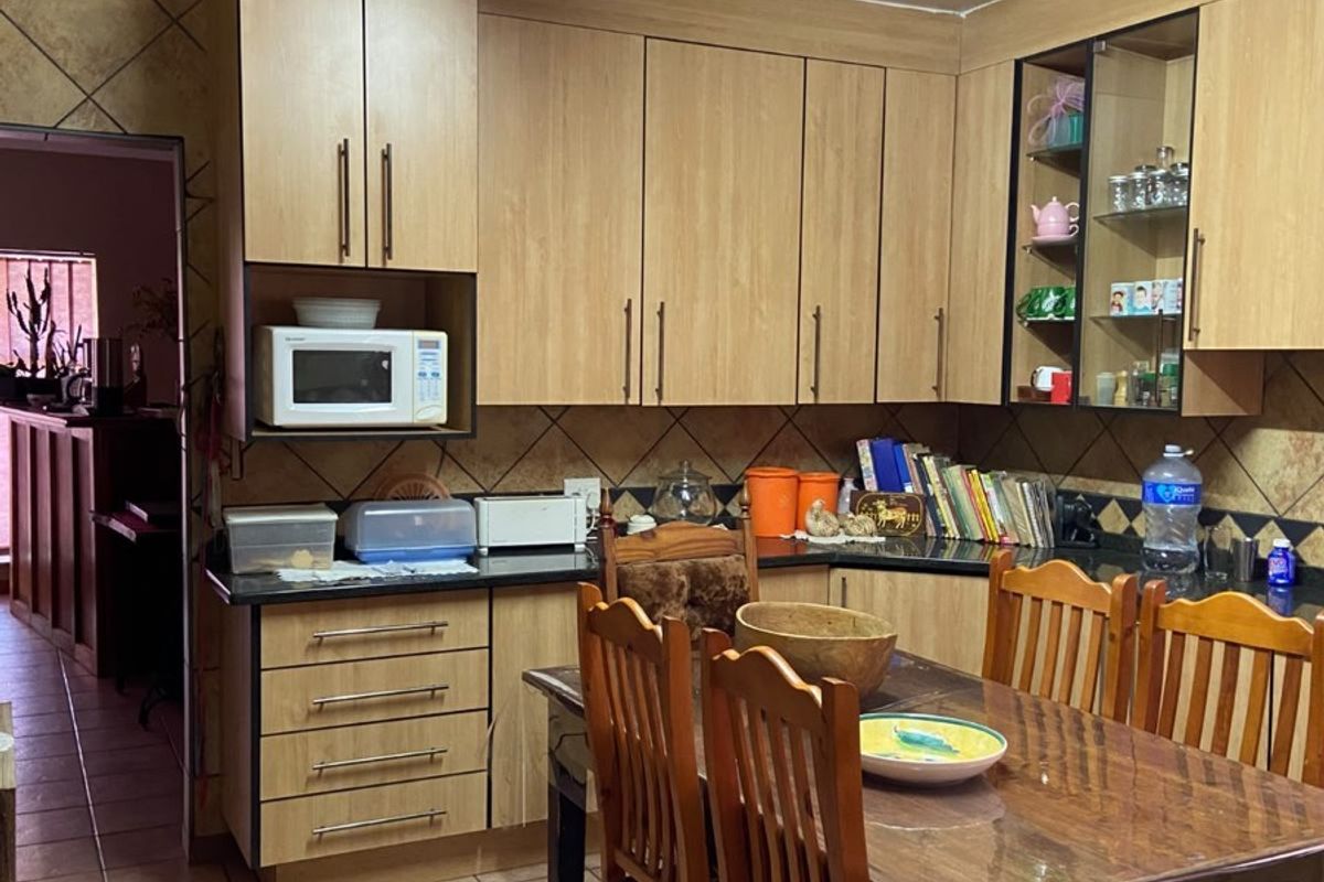 A functional kitchen featuring laminate cabinetry, tiled backsplash, and ceramic flooring, offering a practical layout with integrated microwave space.