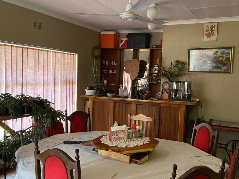 Dining room featuring tiled flooring, a ceiling fan, vertical blinds, and a built-in wooden bar area.