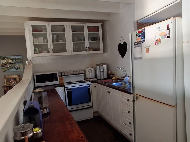 A functional kitchen featuring white cabinetry, a freestanding stove, a sink, and exposed ceiling beams, providing a practical workspace with a classic aesthetic.