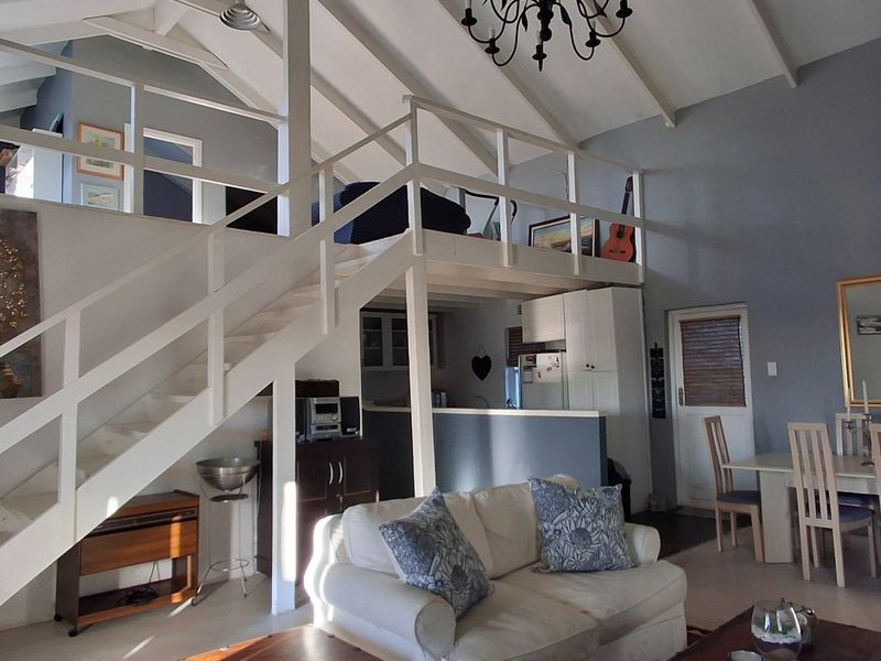 Spacious open-plan living area featuring a vaulted ceiling with exposed rafters, a mezzanine level, and a functional kitchen layout.