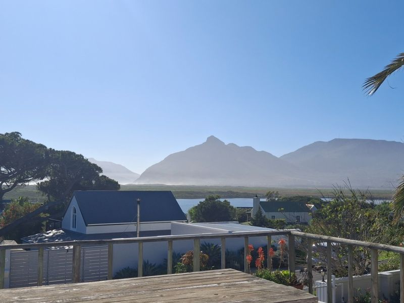 Elevated outdoor view overlooking the surrounding landscape, lagoon, and distant mountains from a wooden balcony.