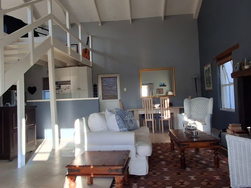 Spacious open-plan living area featuring a mezzanine level, timber staircase, and a traditional fireplace with exposed beam ceilings.