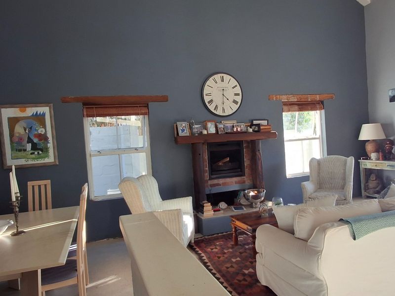 Spacious open-plan living and dining area featuring a vaulted ceiling, a central fireplace with a timber mantelpiece, and access to the outdoors.